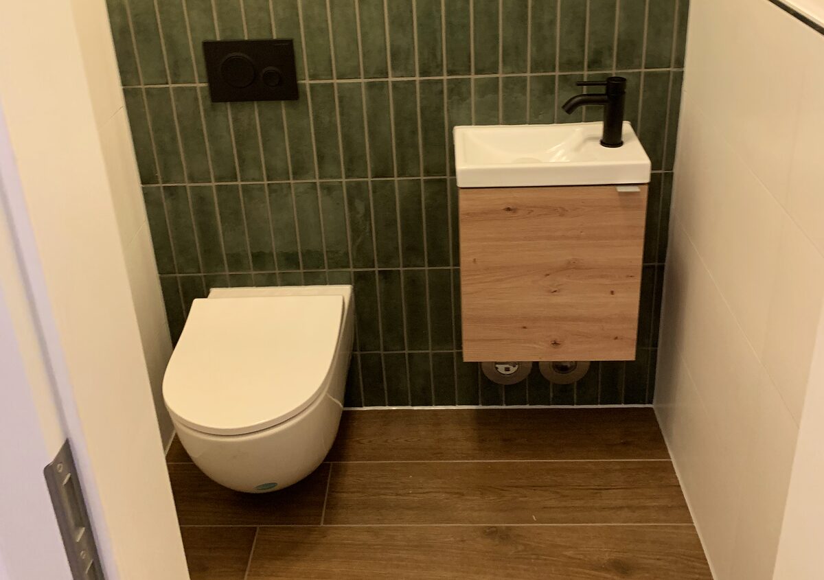 Gäste-WC mit grünen Riemchenfliesen und schwarzer Armatur