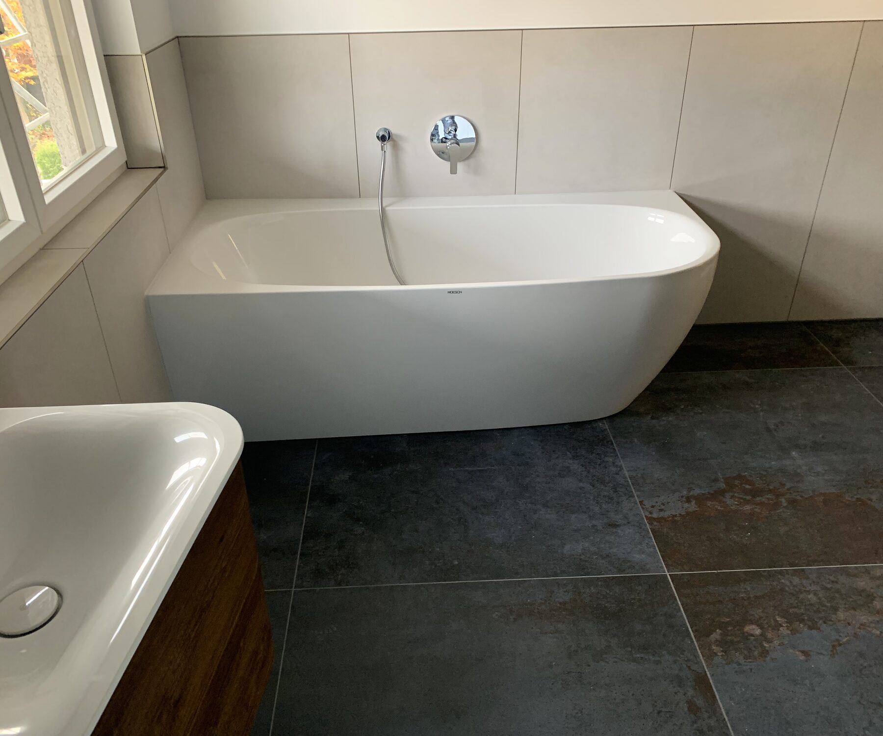 Saniertes Bad mit freistehender Wanne und dunklem Natursteinboden